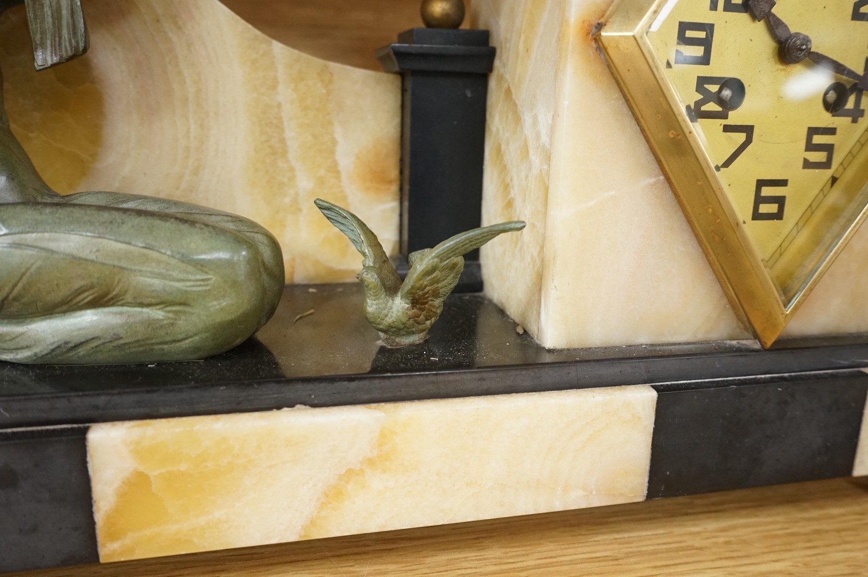 An Art Deco marble and slate clock garniture surmounted with a woman and birds, 52cm wide